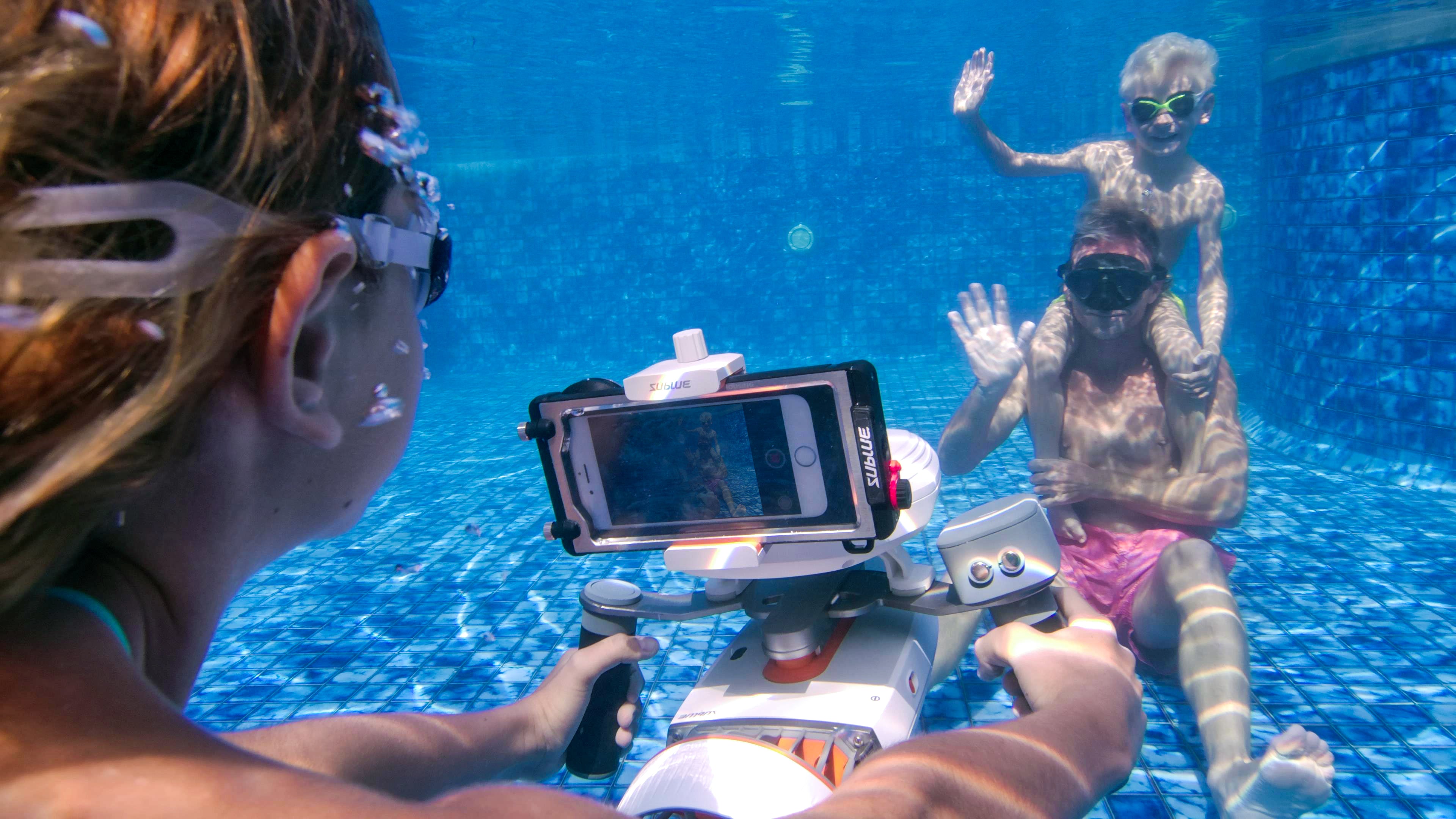 A snorkeler explores underwater near a rocky seabed, with sunlight streaming through the water.