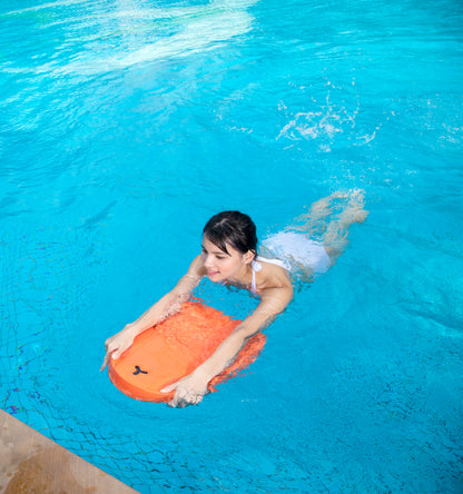 Woman swimming with orange SUBLUE Swii kickboard in blue pool.