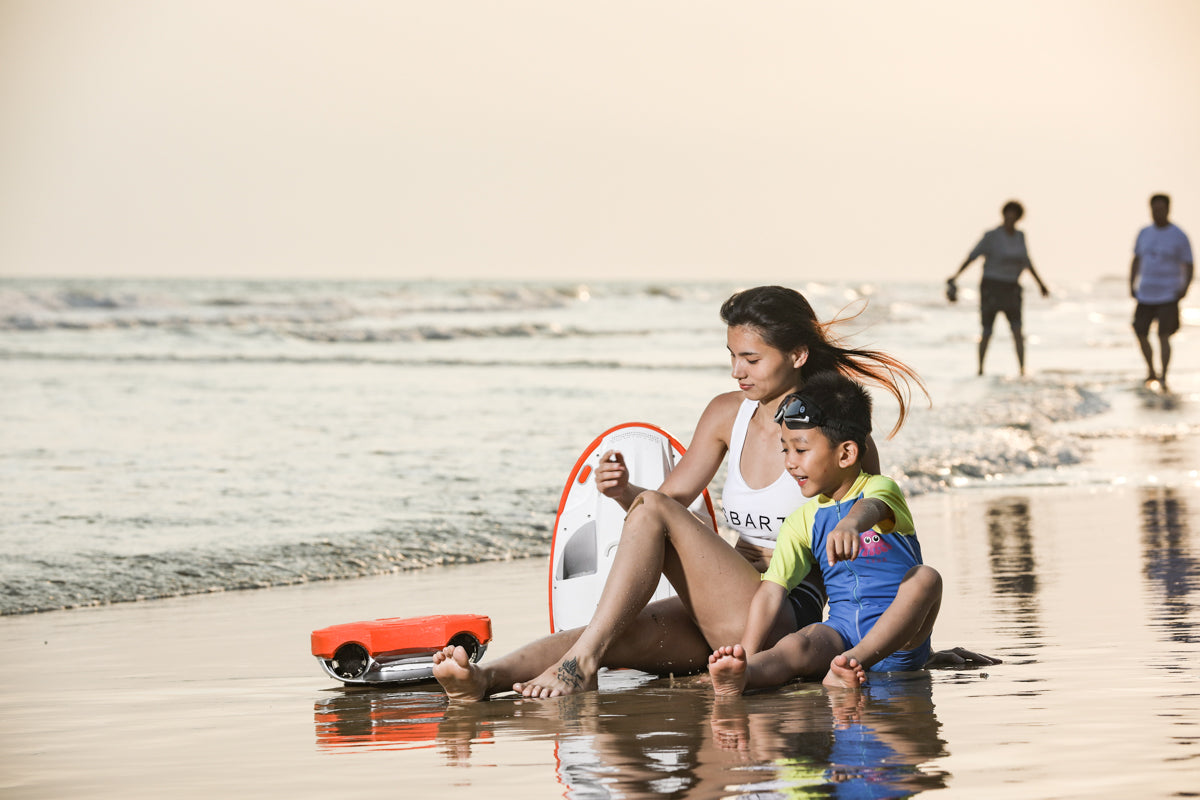 Woman and child on the beach with SUBLUE Swii kickboard, enjoying water fun.