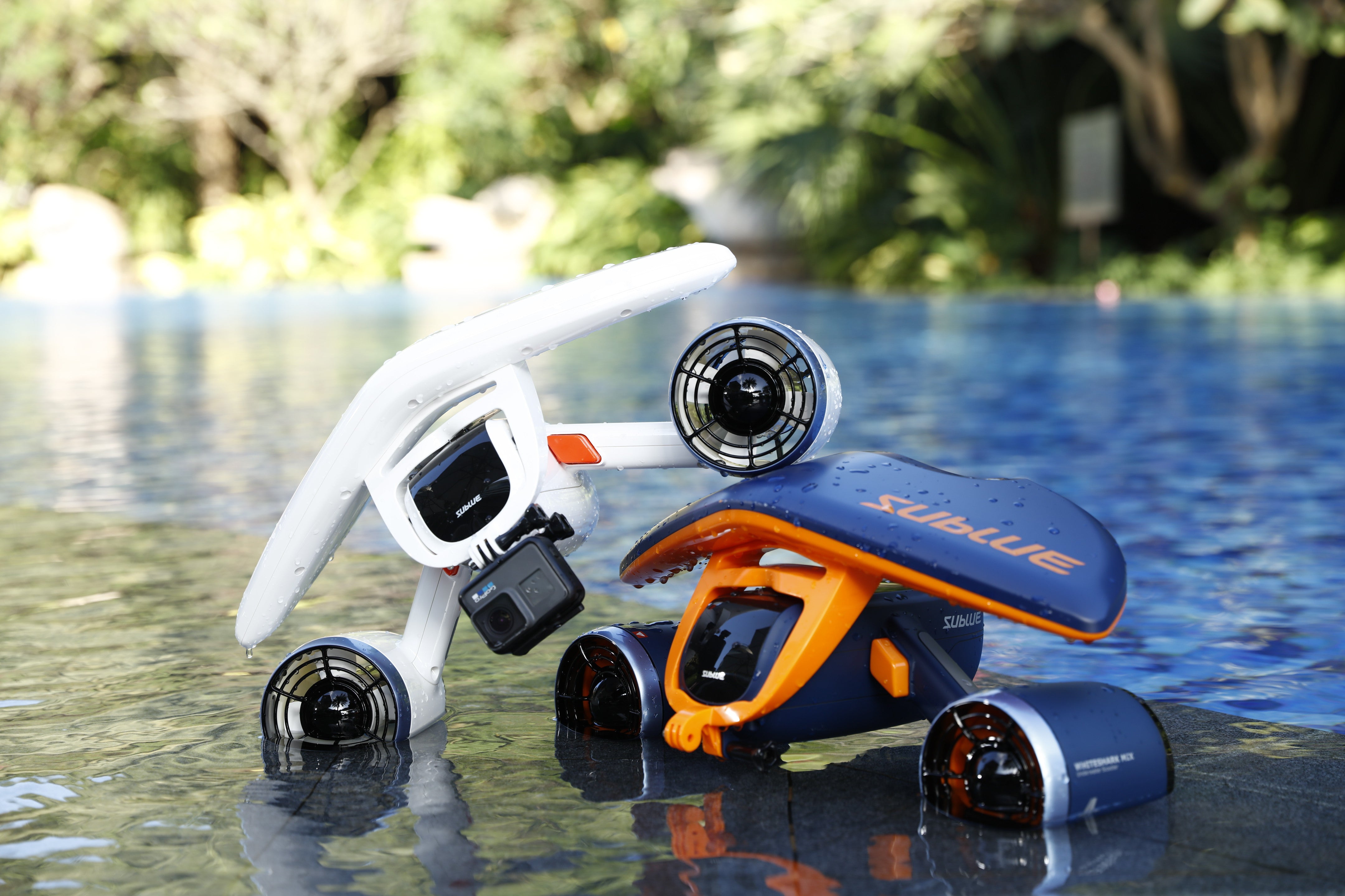 Sublue Mix underwater scooters in orange and white by a poolside.