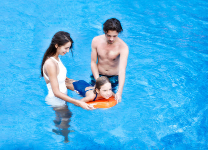 Child practicing swimming skills with SUBLUE Swii kickboard, supported by adults.